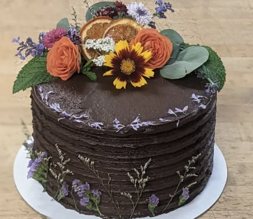 Chocolate layer cake topped with dried orange slices and fresh blooms
