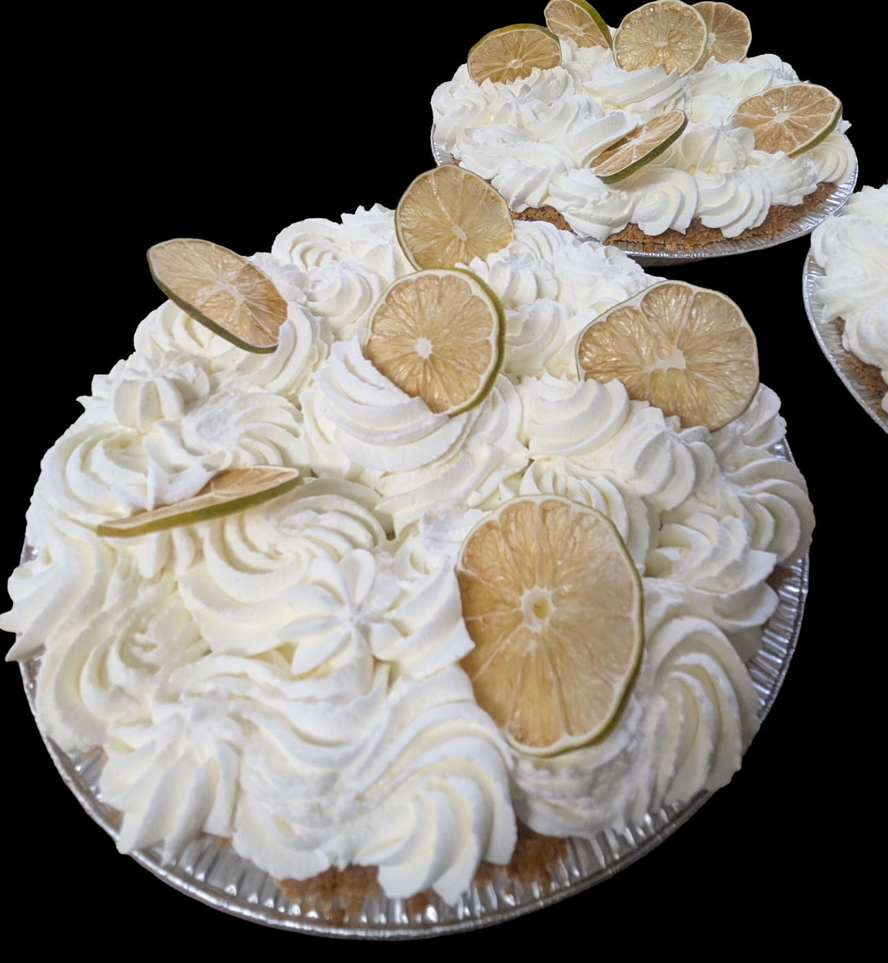 Key lime pies piled with whipped cream and dried lime wheels