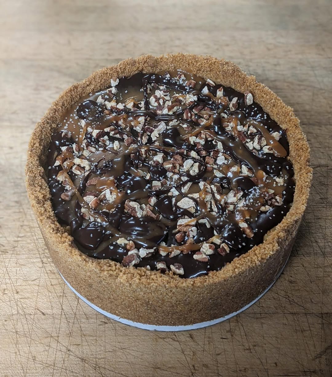 Turtle cheesecake with chocolate ganache, salted caramel and pecans in a graham crust